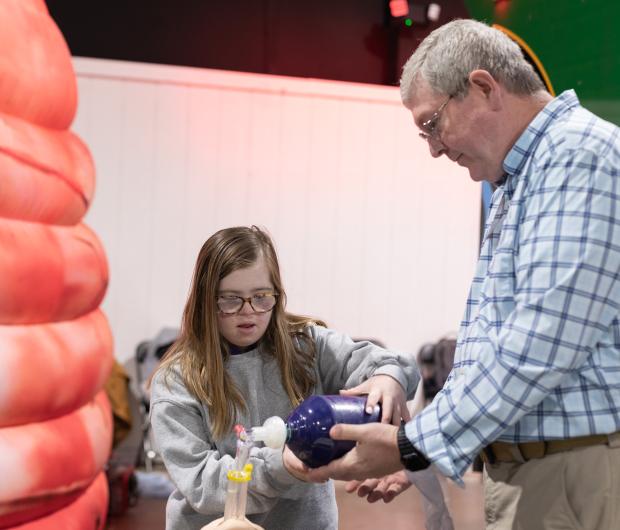 A girl learning how to use a bag valve mask.
