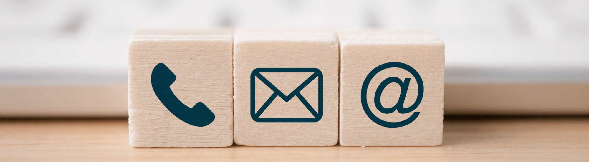 Three blocks with different communication icons sit in front of a computer keyboard.